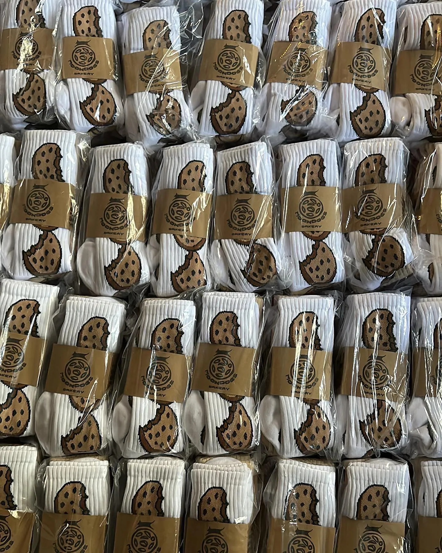 Kraft belly bands wrapped around bagged sock packs, stacked for a drop. The mark sized to be found on a table of product.